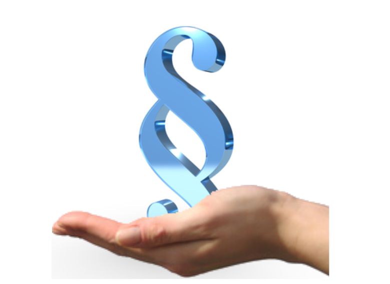 Dłoń trzymająca trójwymiarowy, niebieski symbol paragrafu (§) unoszący się nad otwartą ręką, na jasnym tle.